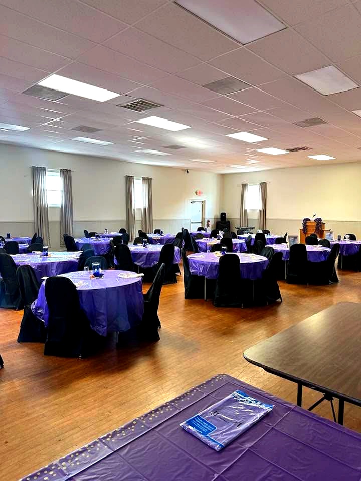 Round tables set with purple linens and black chair covers