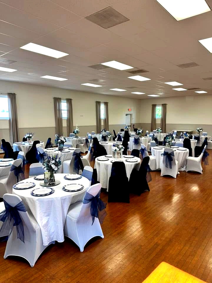 Elegant banquet hall at St. Paul Event Center set with white linens, navy chair sashes, and floral centerpieces