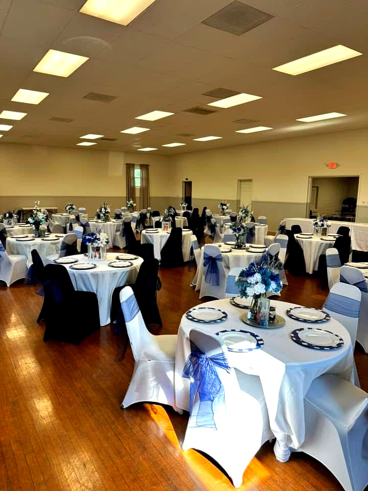 Round tables with white linens, navy chair sashes and floral arrangements