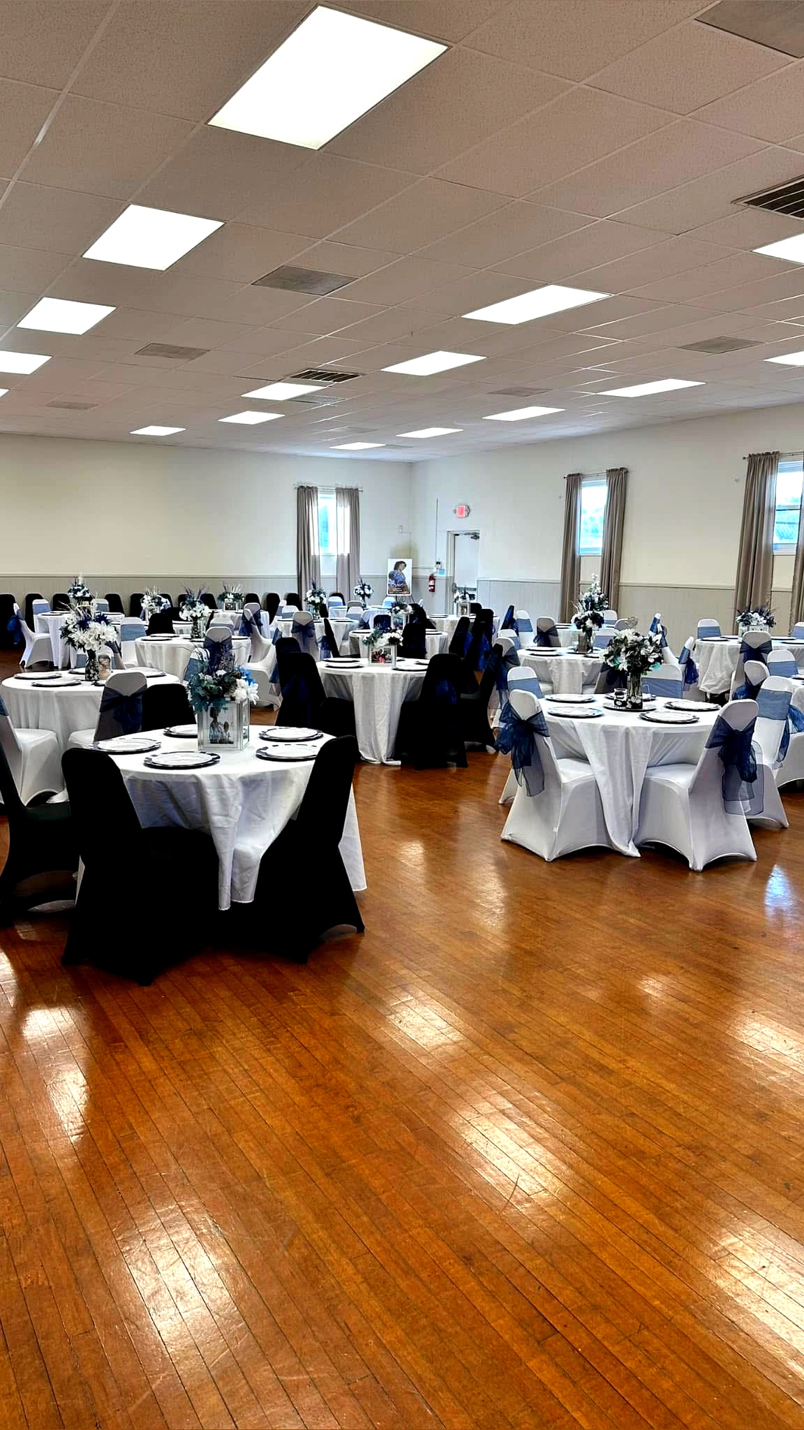 Hall arranged for a gathering with white and black linens and a memory display